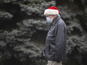 A man wearing a Santa hat and a medical mask walks along Roselawn Drive in South Windsor, Monday, Nov. 30, 2020.
