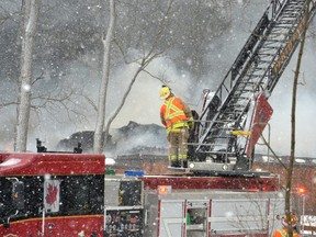 Firefighters operating a ladder truck parked in front of the Forest Motel try to get on top the flames to keep them from spreading further. But flames spread throughout the building just east of Stratford. (Galen Simmons/Postmedia Network)