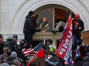 A mob of supporters of U.S. President Donald Trump climb through a window they broke as they storm the U.S. Capitol Building in Washington, U.S., January 6, 2021. REUTERS/Leah Millis/File Photo