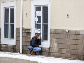 A woman speaks to her grandmother on the telephone while they look at each other through a window at a long-term care home in Southwestern Ontario during a COVID-19 outbreak in January 2021. (Derek Ruttan/The London Free Press)