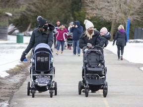 Jessica Dockrill pushes her seven-month-old daughter Brinlee while Jenny Britt carries her 11-month-old daughter Rowen during a walk through Springbank Park in London, Ont. on Tuesday January 19, 2021. (Derek Ruttan/The London Free Press)