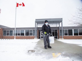 Custodian Murray Campbell spreads de-icer at the entrance to West Oaks French immersion elementary school in London on Thursday. Earlier that day, Education Minister Stephen Lecce announced students in the Thames Valley District and London District Catholic school boards will be return to the classroom on Monday. (Derek Ruttan/The London Free Press)
