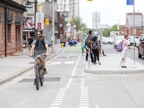 A cyclist travels along the King Street bicycle lane while others wait for the bus in London on the concrete island in this 2019 photo. (Free Press file photo)