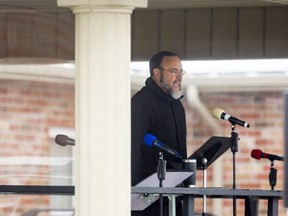 Pastor Henry Hildebrandt welcomes his congregation and those protesting on the road nearby to a drive-in service at Aylmer's Church of God. Photo taken Jan. 4, 2021. (Mike Hensen/The London Free Press)