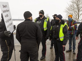 A protester who entered the property of the Church of God in Aylmer stands behind Aylmer police as church supporters challenge him on Sunday January 3, 2021. (Mike Hensen/The London Free Press)