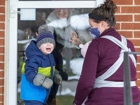 Doug and Yvonne Peckham greet their neighbours Hudson Dutot, 2, his mom Jenna and little sister Hadley, 21 months, as they meet through the front door as the neighbours continue to be close throughout the lockdown in London. Photograph taken on Wednesday January 6, 2021. (Mike Hensen/The London Free Press)