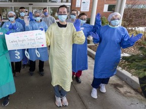 Navdeep Saini and Sydney Kitching hold up a sign Thursday celebrating 300 days of COVID-19 assessment at the Carling Heights Optimist Community Centre without a staff infection. (Mike Hensen/The London Free Press)