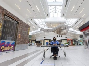 Ujjwal Creet, a security guard at White Oaks Mall, sits alone where he screens incoming customers for COVID risks in the largely closed shopping centre in London. (Mike Hensen/The London Free Press)