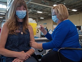 Theresa Burns, a long-term care worker at Greenwood Court, receives a COVID-19 vaccination from Debbie Karz, a public health nurse with the Middlesex-London Health Unit. (Chris Montanini, Postmedia Network)