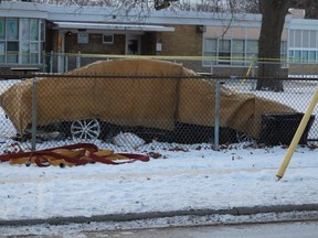 A car covered by tarps sits in the school yard at Hanna Memorial public school in Sarnia. The car's driver died in the crash early Wednesday, sparking a probe by the province's Special Investigations Unit. (Paul Morden/Sarnia Observer)