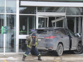A tow truck operator works to remove a vehicle that crashed into a TD bank in west London Tuesday afternoon. JONATHAN JUHA/The London Free Press