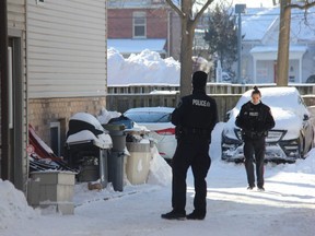 Two London police officers remained outside a two-story home at 153 Sydenham St. Two people were arrested Wednesday morning after police received reports of an armed man inside a house on the street. (JONATHAN JUHA/The London Free Press)