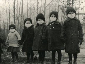 Masked up, six children in a southern Alberta coal-mining family strike an arresting pose during the 1918 Spanish influenza pandemic, a black-and-white throwback to a common public health precaution - facial masks - widely required now to help stop the spread of COVID-19. (Canmore Museum)