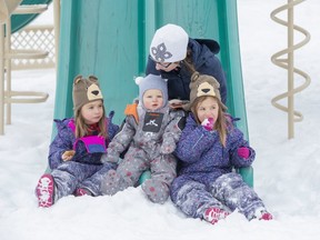 Three-year-old twins Isla (left) and Alice Wasko take a snack break while enjoying the playground equipment at Thamesbridge Park in Riverbend with mom Marleen and nine-month-old brother Bryce on Tuesday. (Derek Ruttan/The London Free Press)
