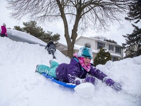 Cordelia Hawley (10) sleds down an almost house-high pile of snow while visiting friends Haven Murray (10) and her brother Tirian (8) in London on Thursday February 18, 2021. (Derek Ruttan/The London Free Press)