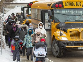 Students and parents file past buses that some students use to get home, while others walk with their parents as they left Eagle Heights public school for the walk home after the first day of in class schooling this year in London, Ont. (Mike Hensen/The London Free Press)