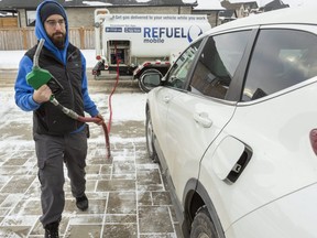Adam Egan of ReFuel Mobile hauls a gas line to a customer's vehicle in London on Tuesday, Feb. 9, 2021. The company delivers gasoline using a mobile truck and customers pay with an app, and only need to leave their gas cap opened. Mike Hensen/The London Free Press/Postmedia Network