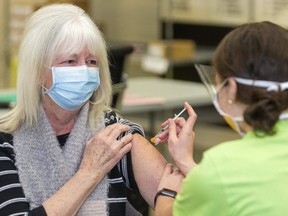 Anne Doherty of Middlesex County, an essential caregiver to her two parents, receives a COVID-19 vaccination from public health nurse Hannah Currie at the Caradoc community centre in Mt. Brydges, west of London. (Mike Hensen/The London Free Press)