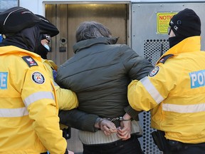 Toronto police officers, enforcing provincial emergency COVID measures, detain a man who was part of a group protesting against COVID-19 restrictions at Dundas Square in Toronto January 23, 2021.