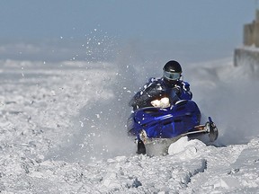 A snowmobiler cuts through snow while riding on the surface of Lake St. Clair near the Belle River pier in January 2015.