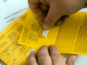 A health-care worker records a vaccination on an International Certificate of Vaccination at a hospital in Germany.