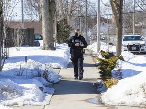 A police constable canvasses the neighbourhood after a bullet was shot through the second floor window of a house at 786 Walker Street in London, Ont. on Tuesday March 2, 2021. The constable was knocking on doors and asking people if they had video surveillance footage of the shooting. (Derek Ruttan/The London Free Press)