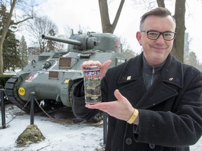 Ward 2 Coun. Shawn Lewis holds a can of Holy Roller beer created by Toboggan Brewing Company in London, and officially released on Friday. Sales of the lager will help with cost of restoring the Holy Roller tank in Victoria Park. (Derek Ruttan/The London Free Press)