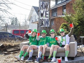 First-year Western University students (from left) Connor Jones, Mason MacDonald, Gavin McFetridge and Ben Van Walleghem enjoy the weather and a few beers on the front lawn of their Richmond Street home in London on Wednesday March 17, 2021. They were drinking every time  passing motorists honked their horn. "We've been through three beers in 15 minutes," said McFetridge. (Derek Ruttan/The London Free Press)