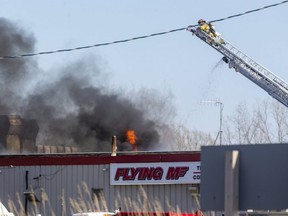 A London firefighter has a bird's eye view of the fire coming through the roof of a back building at the Flying M Truck stop on Colonel Talbot Road between Lambeth and Talbotville in London. No injuries were reported in the blaze Monday that also drew crews from Middlesex Centre and Southwold fire departments. (Mike Hensen/The London Free Press)