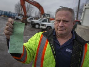 Dale Siefker holds a ticket he received at the Ambassador Bridge for $3,755 while outside his business in Essex on Feb. 28, 2021.