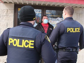 Ron Theriault, owner of Corunna Fitness Centre, speaks Monday with OPP officers outside his gym on Hill Street in Corunna. The OPP officers warned Theriault that he was violating provincial lockdown rules by keeping his gym open. (Paul Morden, Postmedia Network)