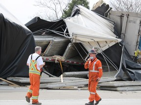 Workers walk past two transport trucks that collided Tuesday on Highway 402 near Christina Street in Sarnia. Drivers of both trucks were taken to hospital and a section of the westbound highway was closed.