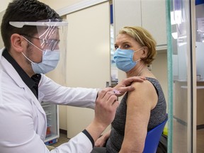 Jennifer Dawes receives an Astra-Zeneca COVID-19 vaccine from pharmacist Adam Aasen at the Shoppers Drug Mart at 603 Fanshawe Park Rd. W. in London on April 6, 2021. Dozens more pharmacies in London and Middlesex County will begin giving out the shots, the province announced Sunday. Derek Ruttan/The London Free Press/Postmedia Network