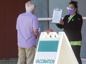 A man reads a list of protocols before entering the COVID-19 vaccination clinic at the North London Optimist Community Centre in London, Ont. on Tuesday. Derek Ruttan/The London Free Press)