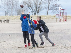 The Brodt brothers, left to right, Maddox, 11, Preston, 9, and Darius, 13, compete for a football thrown by their father Jamy while on the beach at Port Stanley on Friday. The family travelled from their home in London to the beach to enjoy the outdoors and get a family favourite snack from the town's most famous eatery. "We came here to get some Mackie's fries before everything shuts down," said Jamy. (Derek Ruttan/The London Free Press)