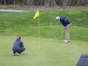 An unidentified golfer watches his putt as another man looks on Monday, April 26, 2021, at The Bridges at Tillsonburg. The course opened Saturday in defiance of the provincial stay-at-home order that closed golf courses and other outdoor recreation activities. No charges or fines have been levied against owners or golfers as of Monday afternoon. (The London Free Press)