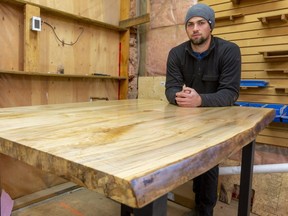 Cole Jordan, who runs Workers Wood Products in London, leans on a bar-height table whose top is made of maple with a live edge, which can retail for about $2,500. (Mike Hensen/The London Free Press)