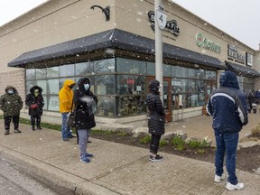 Londoners lined up outside the Shoppers Drug Mart at Wonderland Road and Fanshawe Park Road to get their COVID-19 vaccine shot on Thursday. (Mike Hensen/The London Free Press)