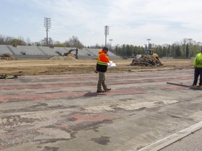 Chris O'Brian and Adam Losier of Playteck Enterprises measure the base for the new running track they will be installing at TD Stadium at Western University. 
(Mike Hensen/The London Free Press)