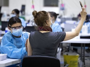 A woman takes a selfie with a health-care worker after receiving the COVID-19 vaccine in Montreal.