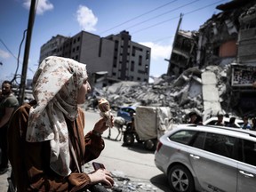 A Palestinian woman is shown in front of the destroyed Al-Shuruq building, toppled by an Israeli air strike, on May 22, 2021, in Gaza City. (Photo by MAHMUD 
HAMS / AFP)