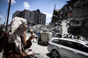 A Palestinian woman is shown in front of the destroyed Al-Shuruq building, toppled by an Israeli air strike, on May 22, 2021, in Gaza City. (Photo by MAHMUD 
HAMS / AFP)