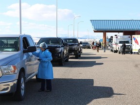 A health worker talks to a driver on the U.S. side of the Carway Border crossing in Montana as cars carrying First Nations members and other Albertans lined up to take advantage of free COVID shots from Montana's Blackfeet Nation April 21.