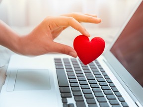 Girl hand take red heart at laptop keyboard for social online love chat and sharing encouragement over internet to fight Covid-19 virus together.