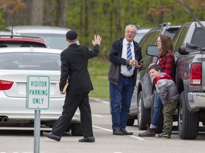 A man carrying a bible waves to Eastern Ontario MPP Randy Hillier as he and an unidentified woman enjoy cigarettes in the company of a child prior to entering the Church of God for Sunday service in Aylmer on Sunday May 9, 2021. Derek Ruttan/The London Free Press/Postmedia Network