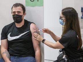 Ryan Gosso, a 25-year-old grocery store employee, receives a COVID-19 vaccine shot from nurse Melissa Thompson at the Earl Nichols Recreation Centre vaccination facility in London on Friday May 21, 2021. (Derek Ruttan/The London Free Press)