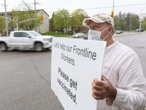 Retired hospital worker Randy Welch aims to help “everybody who has to go to work for us” with a silent vaccination plea at Wonderland Road and Springbank Drive in London. Dismayed by COVID vaccine shopping and hesitancy, he wonders where society would be if we’d hesitated to get the polio vaccine decades ago. (Mike Hensen/The London Free Press)