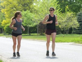 Michelle Pink and Vanessa Kinsley run through the late afternoon heat in London.  Both are long-time runners who ran the virtual half-marathon for the Forest City Road Races this spring and were doing a five-kilometre run on this day. Photograph taken on Friday May 21, 2021. (Mike Hensen/The London Free Press)