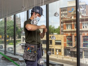 Nick Casaletto, an electrician apprentice for Arcon Electric wires up a cascade of lights that will illuminate new open foyer of the Grand Theatre on Richmond Street. (Mike Hensen/The London Free Press)