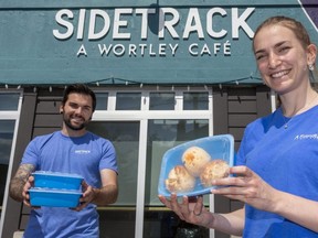 Richie Bloomfield, co-owner of Sidetrack: A Wortley Cafe, and Jacquie Hutchings of A Friendlier Company hold the company's reusable plastic trays that come back to the store for a deposit and can be used hundreds of times. (Mike Hensen/The London Free Press)